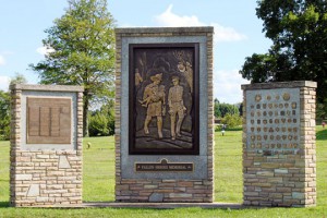 Fallen Heroes garden memorial featuring a bronze relief image of firefighter carrying little girl to safety next to a police officer and two monuments on each side.