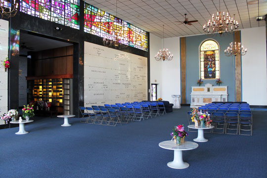 Mausoleum Chapel with stained glass features and chairs facing alter with flowers on round tables.