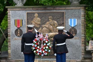 Memorial Day ceremony with soldiers saluting war memorial.